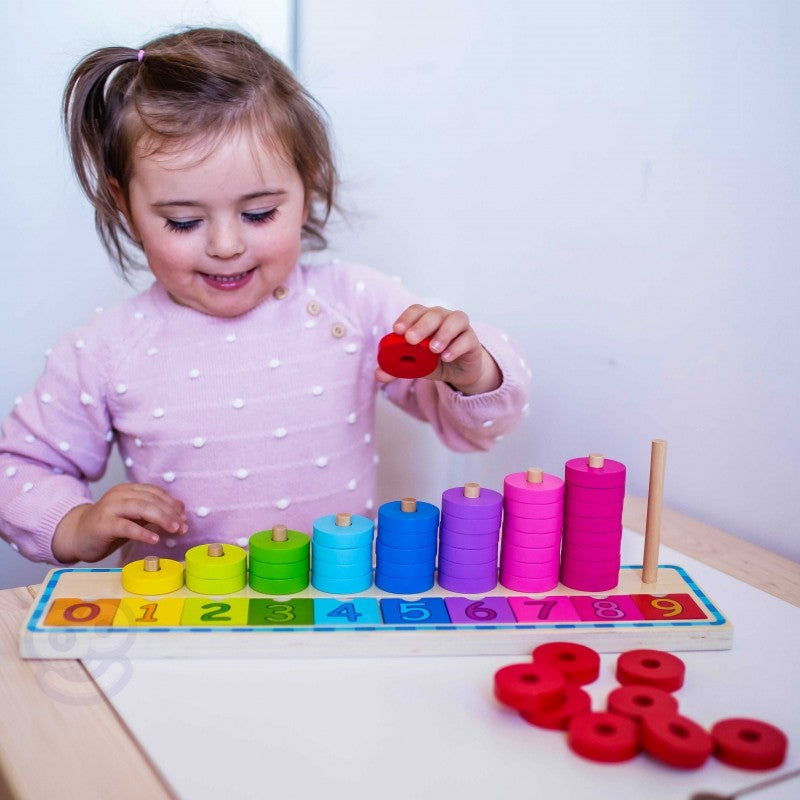 close-up of a child's hands placing a green counting puzzle piece onto the numbered wooden board