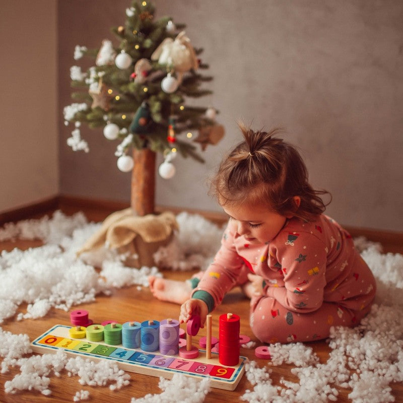 close-up of a toddler's hands placing a bright red counting puzzle piece into its wooden slot