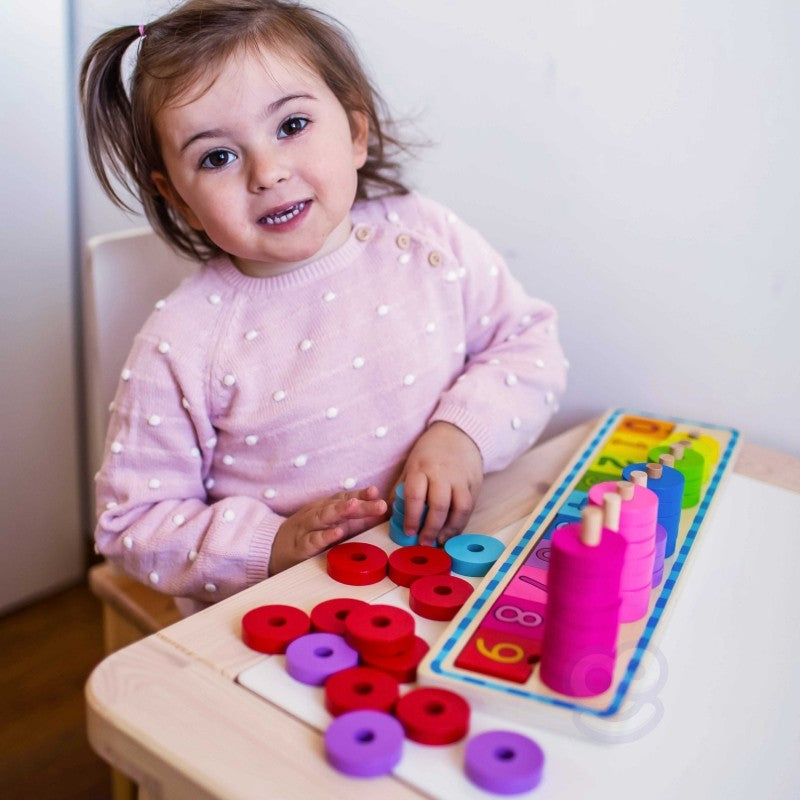 a child's hand placing a bright yellow circle onto the wooden counting puzzle board