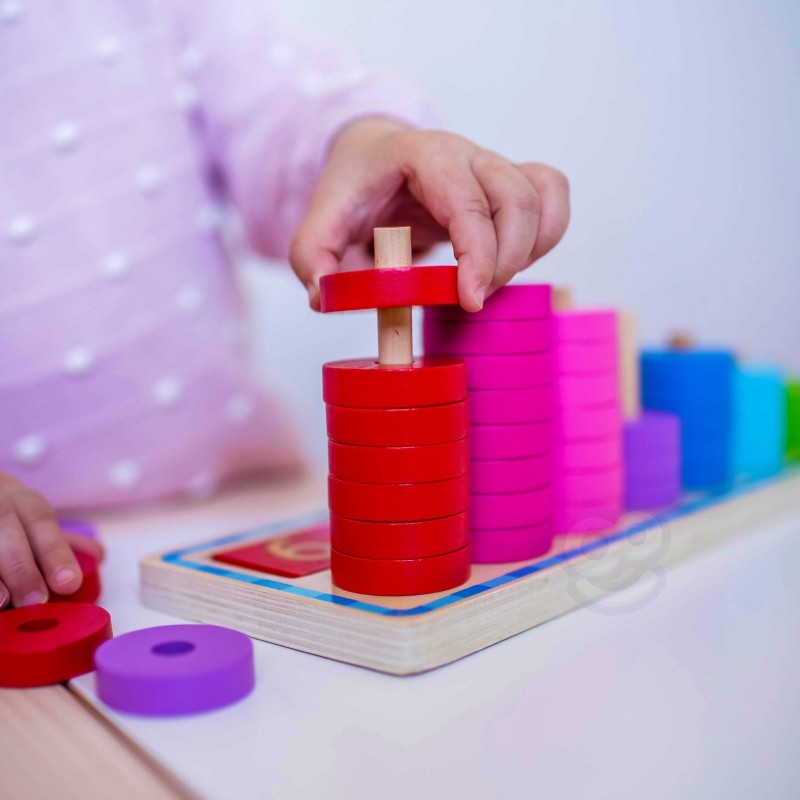 a playful toddler's hand placing a bright yellow circle onto the wooden counting puzzle