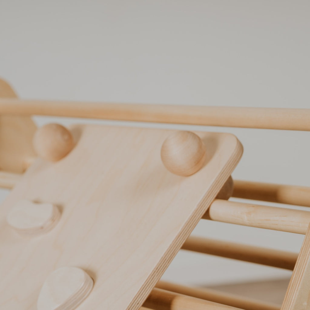 a child's hand gripping a textured rock hold on the birch plywood climbing ramp