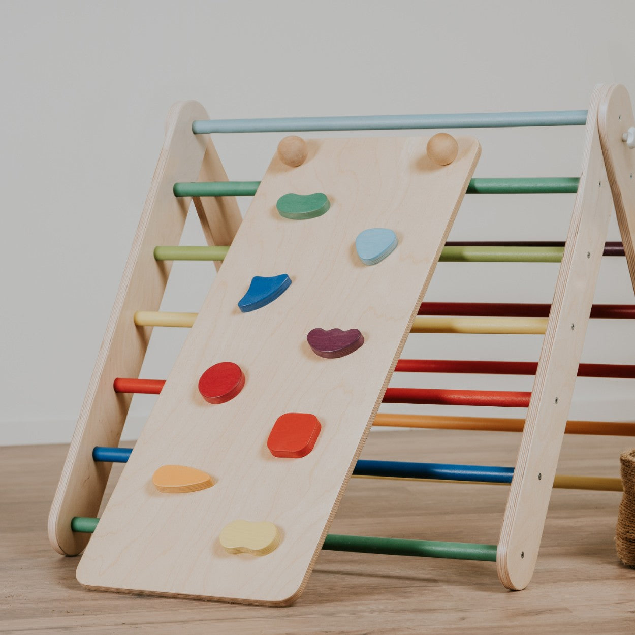 a child's hand gripping a colorful rock hold on the playful rainbow climbing ramp