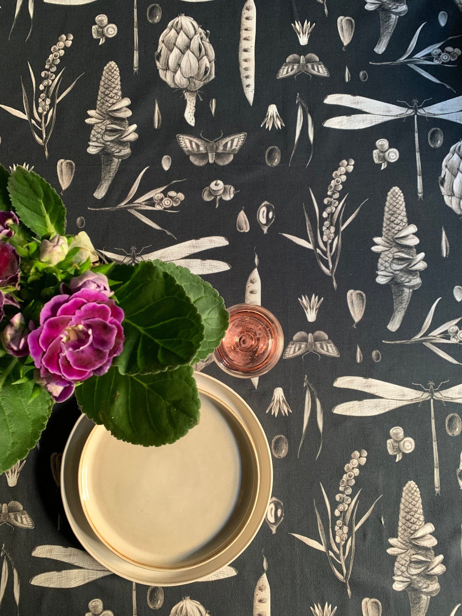 a soft cotton tablecloth with a subtle seeds carbon print, laid gently on a table in warm morning light