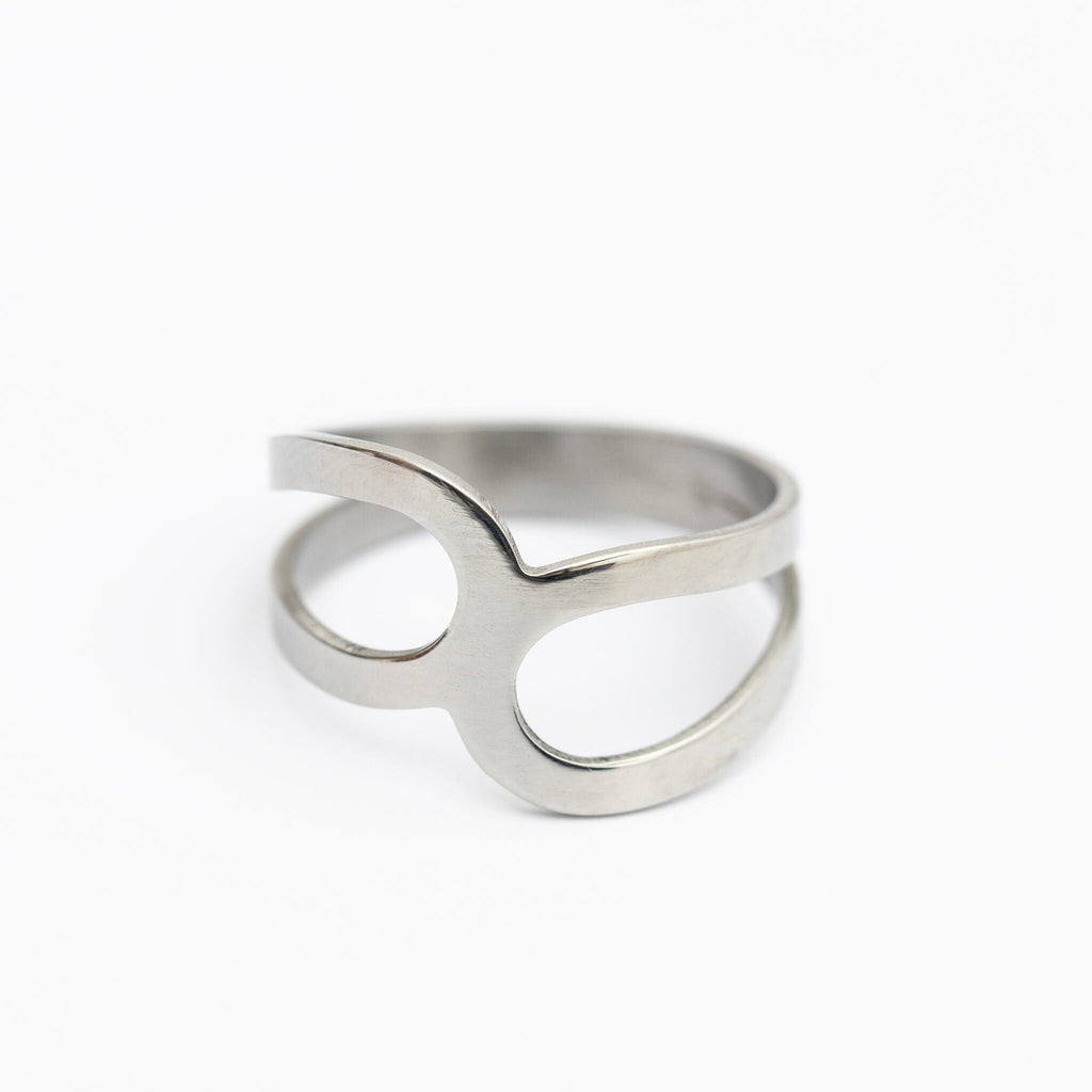 a playful close-up of the polished stainless steel ring x, catching the light with a fun, weightless sparkle