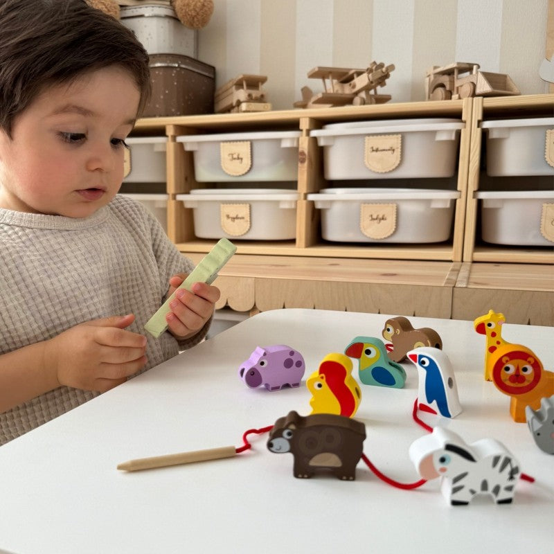 close-up of a child's hands threading a wooden giraffe block onto a string