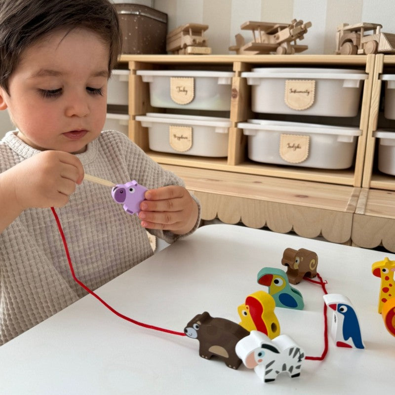 close-up of a child threading a wooden giraffe block onto a string