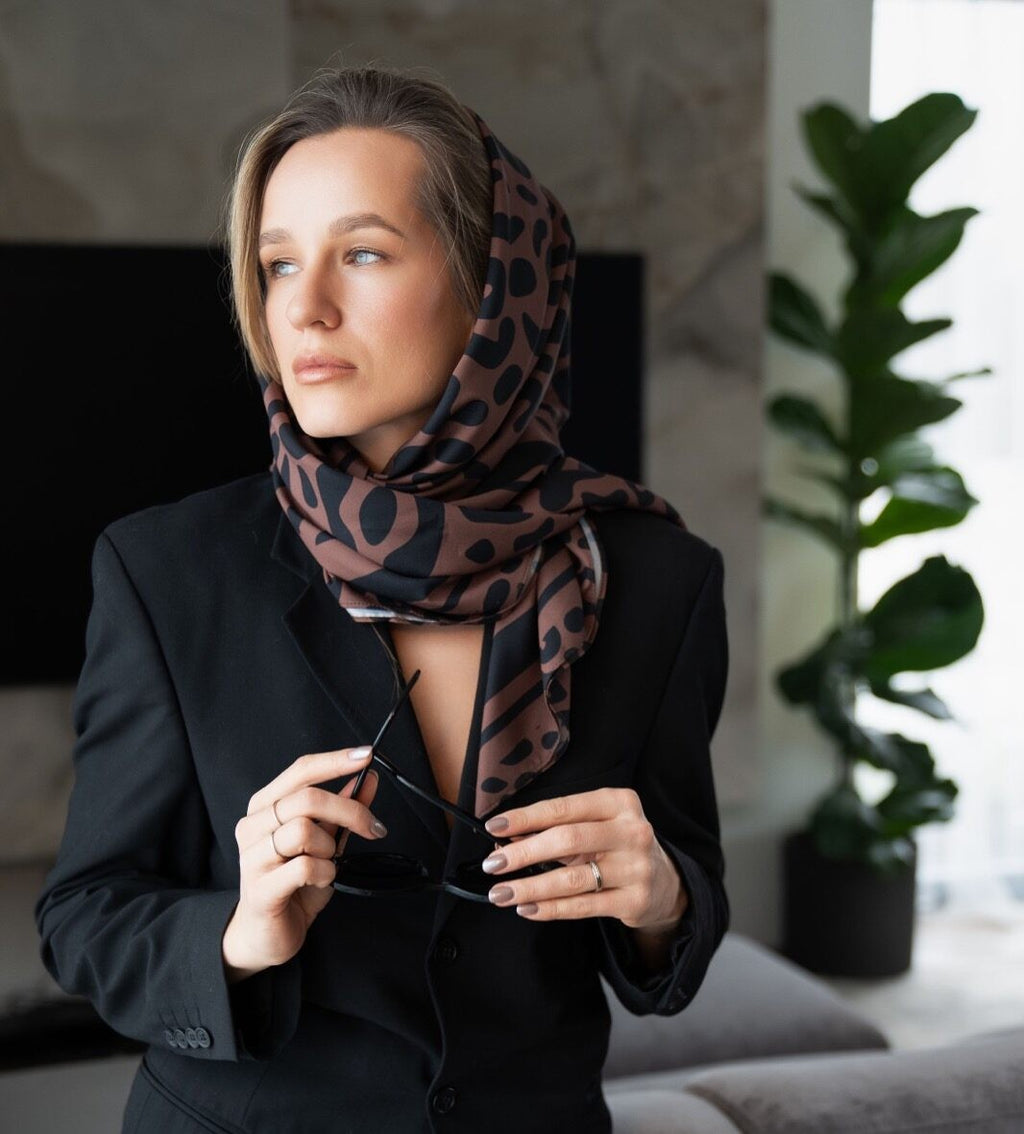 a bold confident woman tying a classic leopard print scarf around her neck