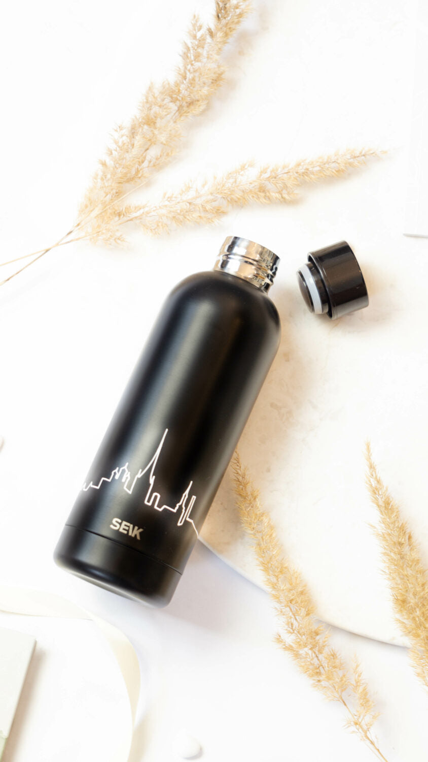 playful close-up of the tallinn skyline water bottle with a sunlit sea-blue background