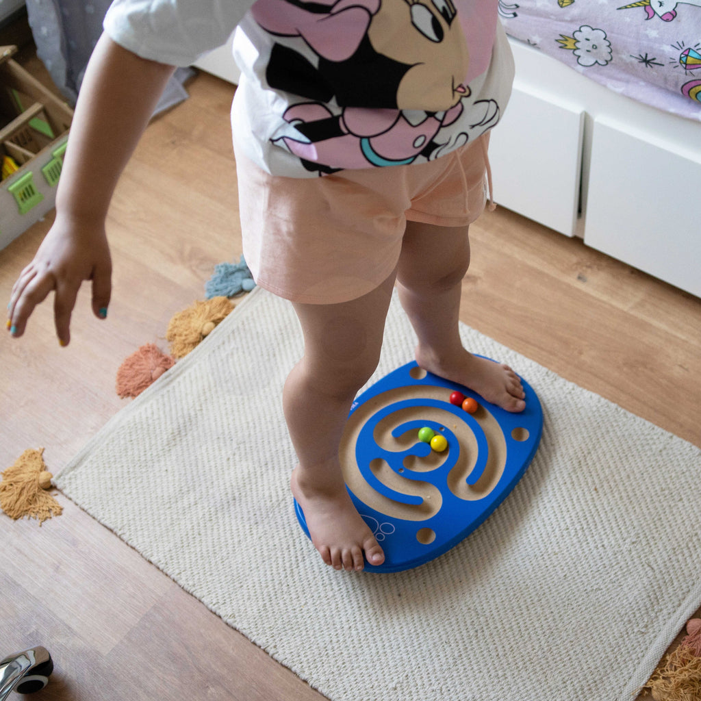 child balancing on wooden maze board with bright balls, focusing on coordination and fun