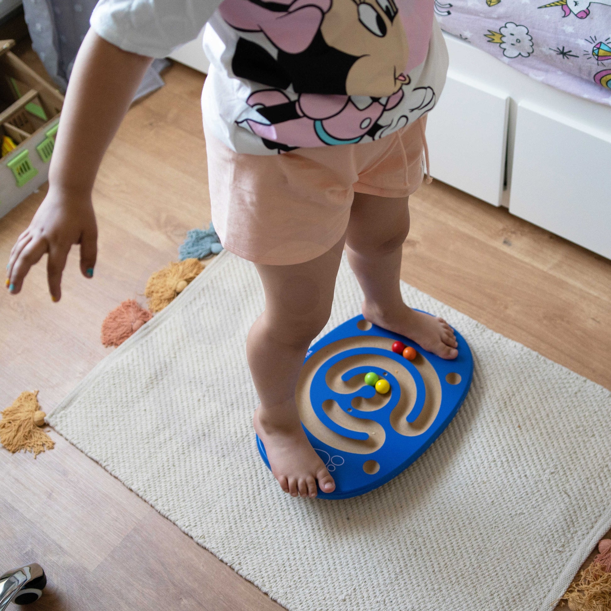 child balancing on wooden maze board with bright balls, focusing on coordination and fun