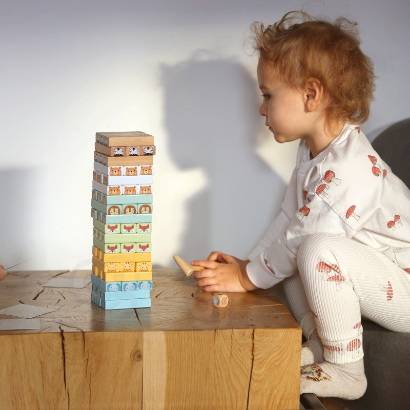 close-up of a child's hands carefully placing a pastel wooden block on the shaky tower game