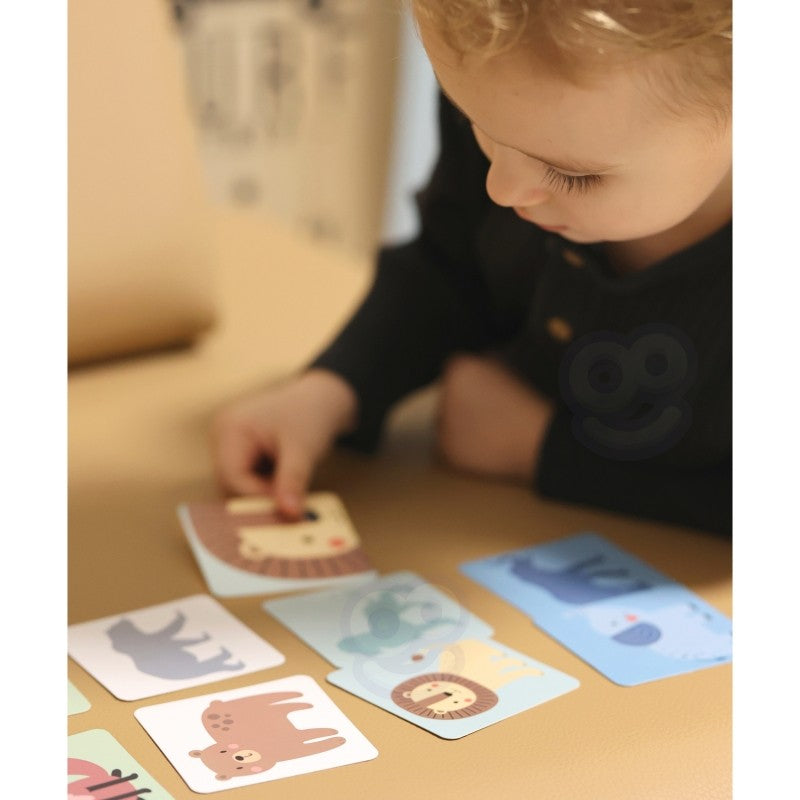 close-up of a child's hands carefully placing a pastel wooden block on the shaky tower game
