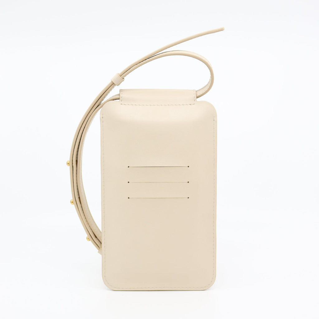 playful beige leather crossbody phone bag with gold buttons on a sunny day