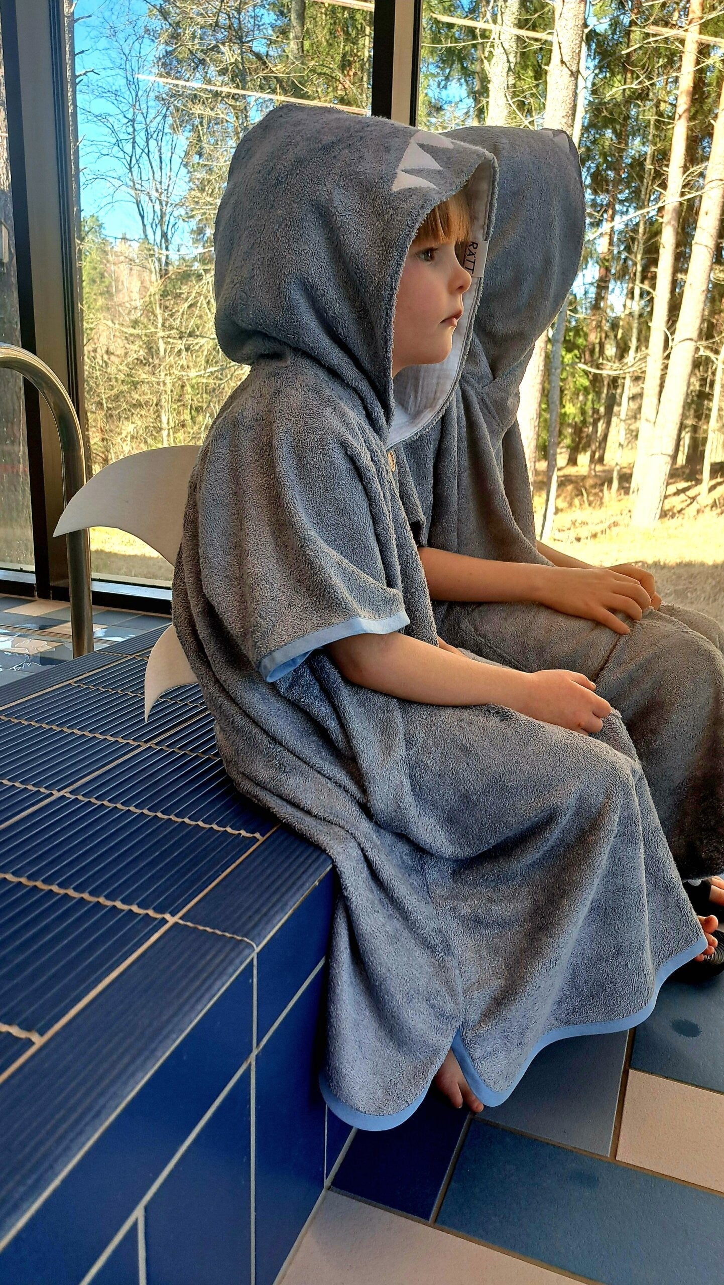 toddler in soft bamboo shark poncho, cozy hood up, smiling after a swim