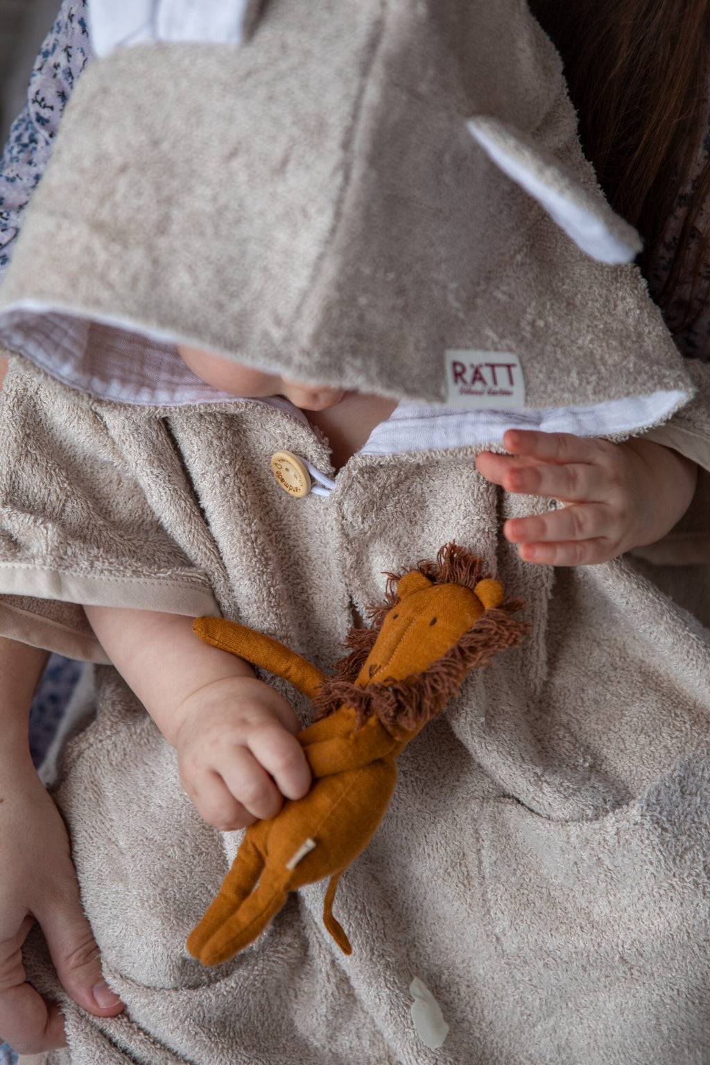 toddler in cozy bamboo poncho laughing, showing off the soft hood and handy pockets after a swim