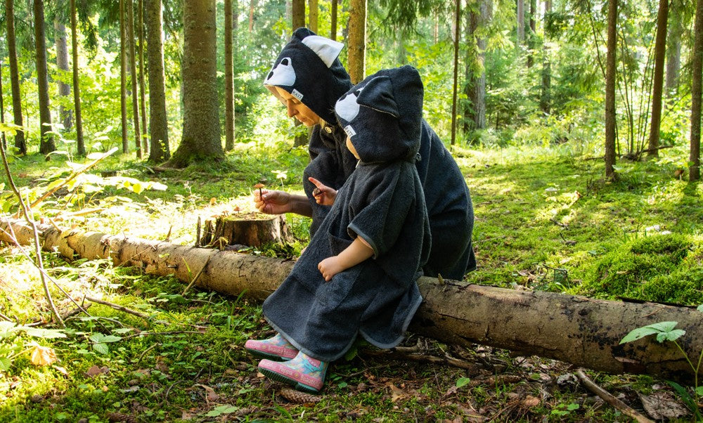 a toddler laughing in a wolf poncho, twirling to show off its soft hood and pockets