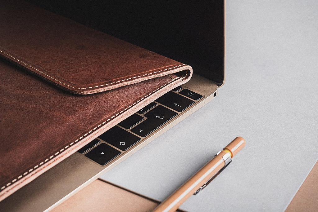 elegant slim note sack for a 13-inch laptop, showcasing its refined vegetable-tanned leather texture in a warm, ambient light