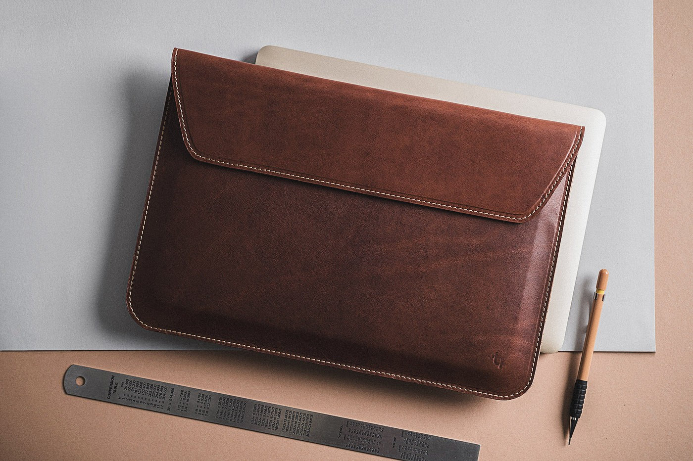 slim note sack laptop case open on a rustic wooden desk with natural morning light highlighting its premium leather texture