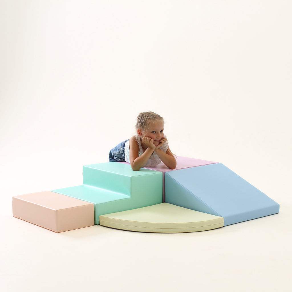 a child's joyful hands climbing a soft pastel foam corner climber block