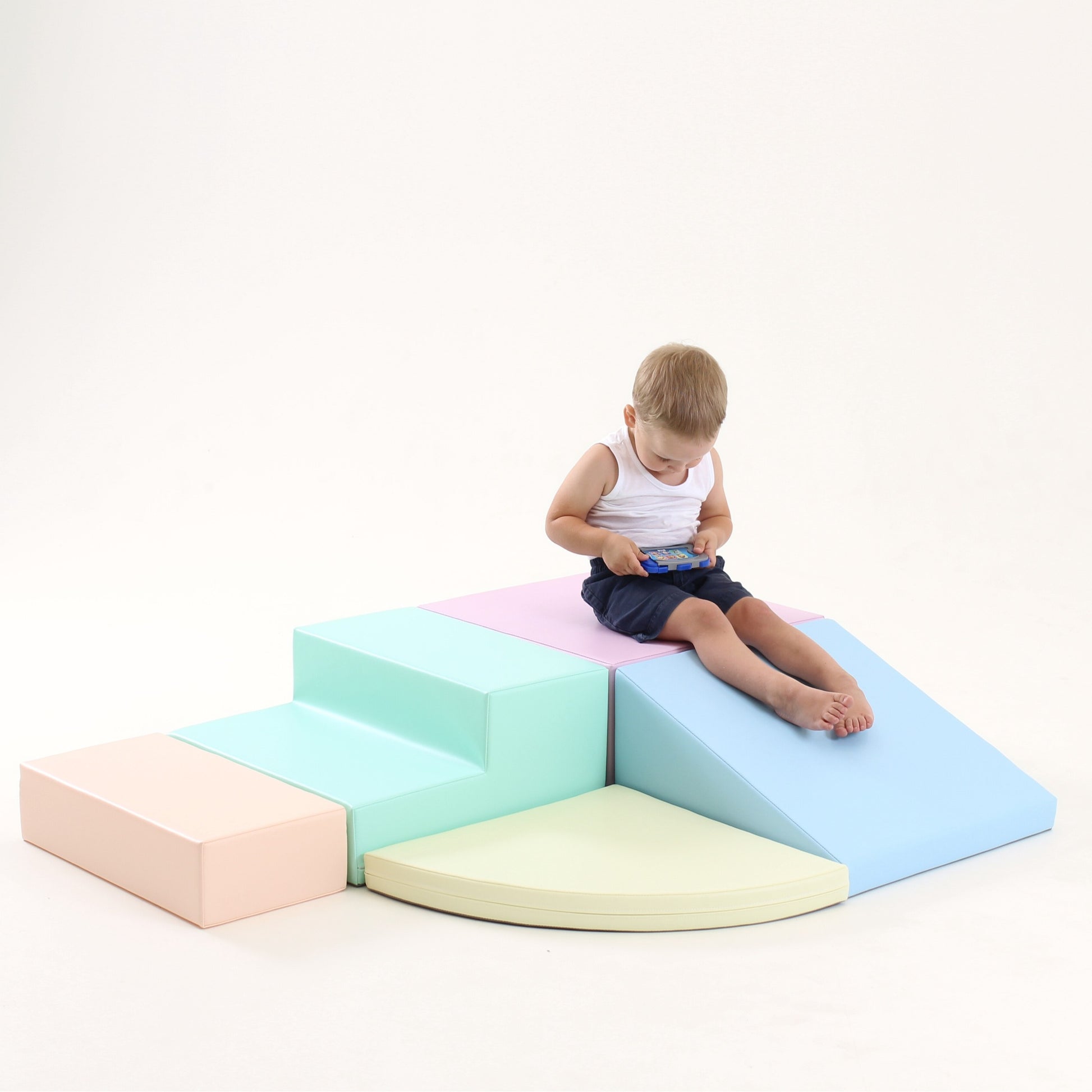 a child's hand reaching for a soft pastel corner climber foam block in warm morning light