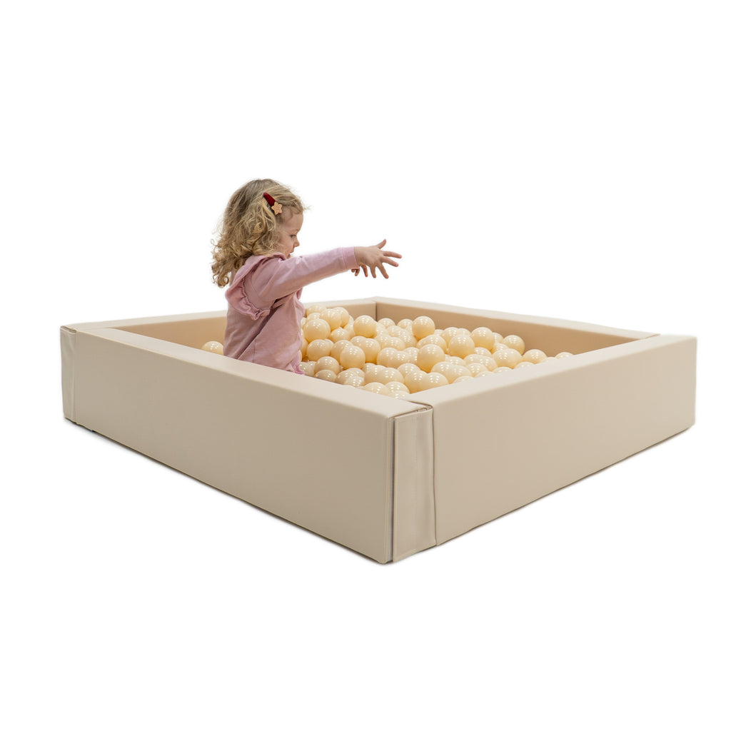 beige soft play ball pit for babies in a bright, sunlit nursery setting