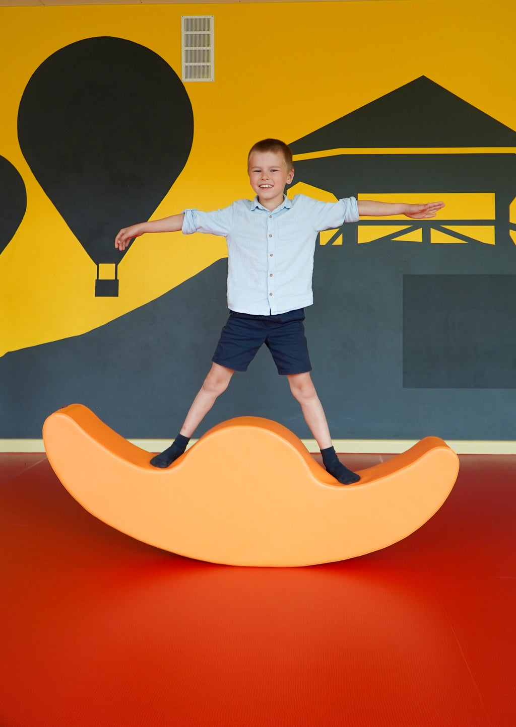 vibrant orange buddy double rocker for two kids in a bright, modern playroom setting