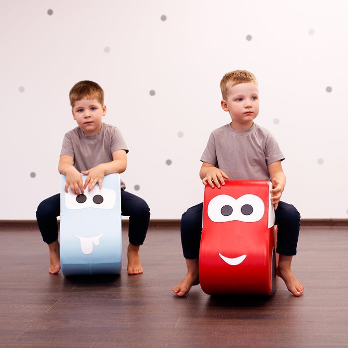 smiling toddler driving a bright red iglu foam car during a playful indoor adventure
