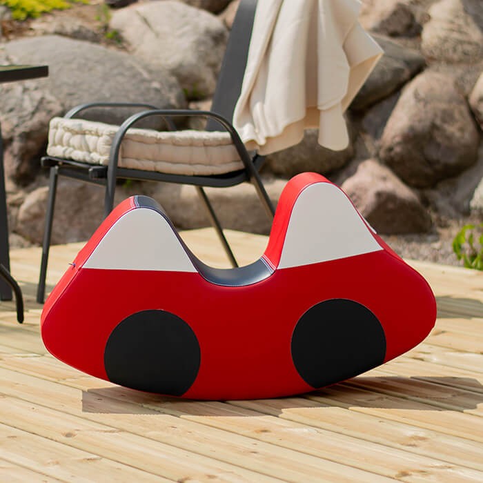 a child's hand steering the soft red iglu ride-on car on a hardwood floor