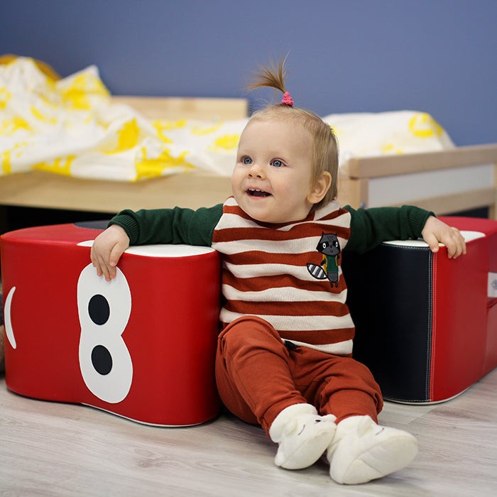 practical view of a child playing with the soft foam red car on a hardwood floor