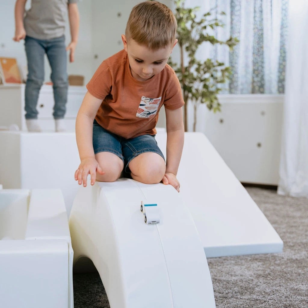 adorable toddler giggling on a soft white banana rocker, boosting balance and joy