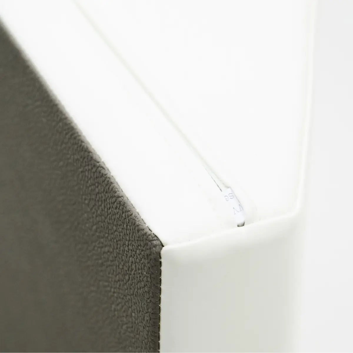 a playful toddler peeking out from the end of a soft white play tunnel with a bright smile