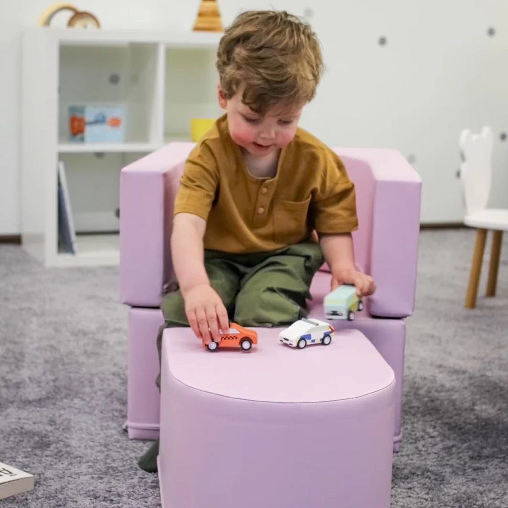 a child's pink snoozy sofa chair unfolded as a play mat for stretching out with toys