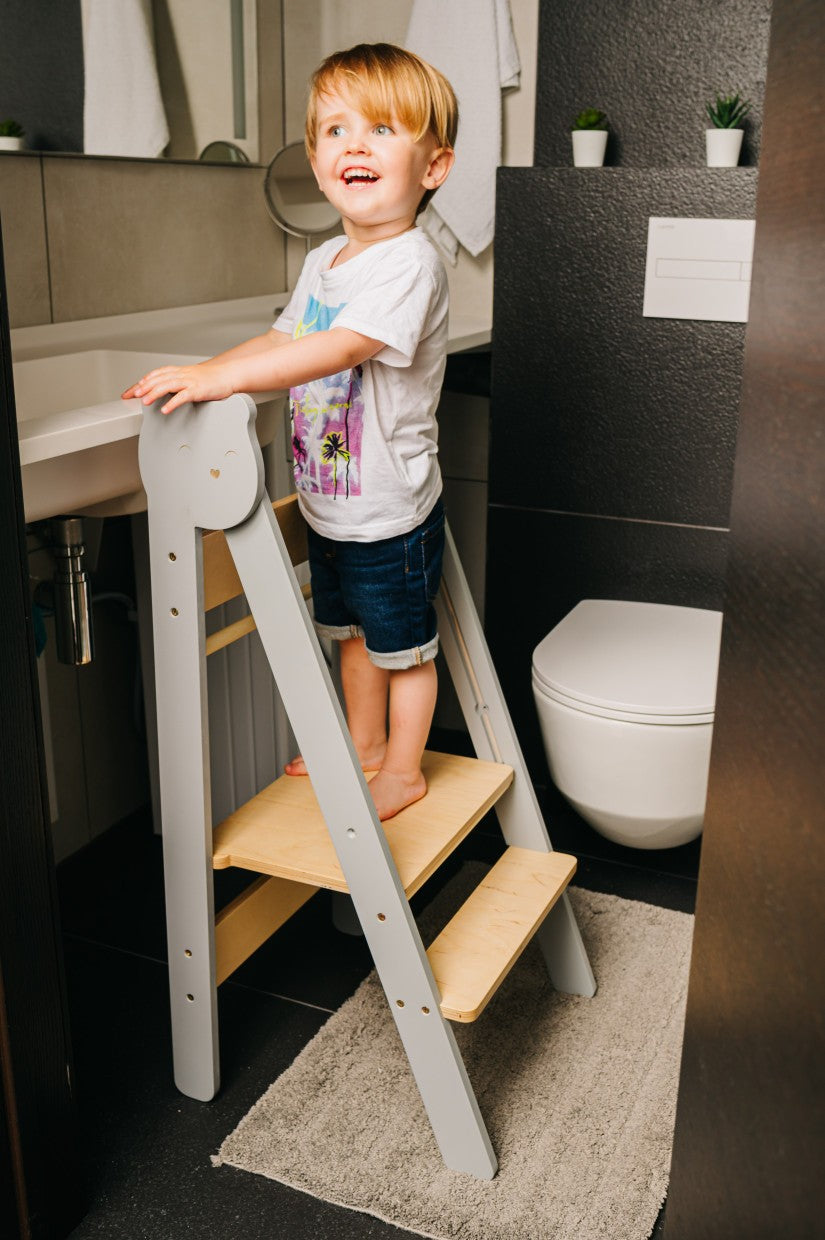 a playful toddler reaching for cookies on the counter with a foldable wooden step stool