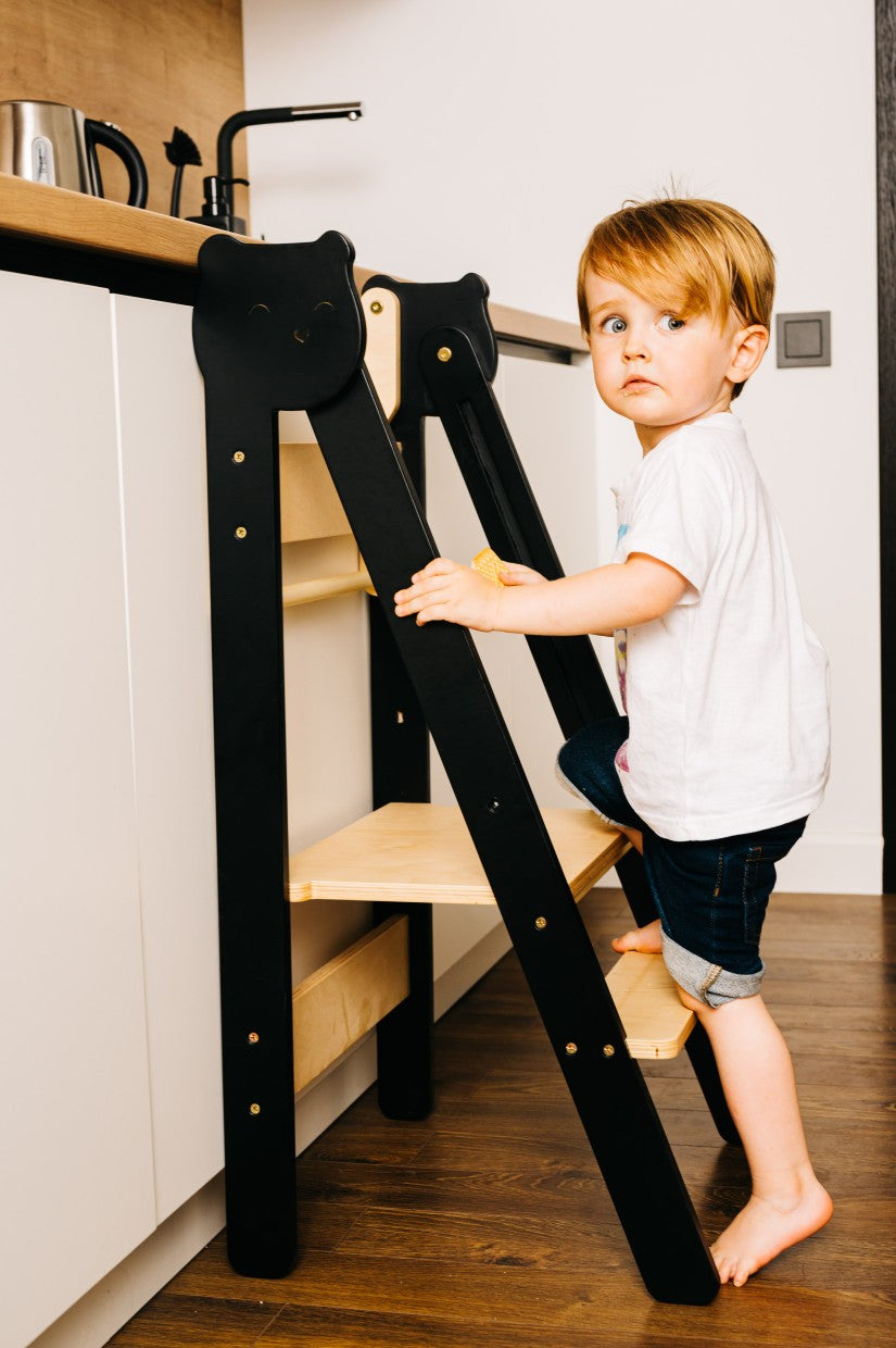 foldable baltic birch step stool in a bright kitchen, folded flat against a cabinet for compact storage