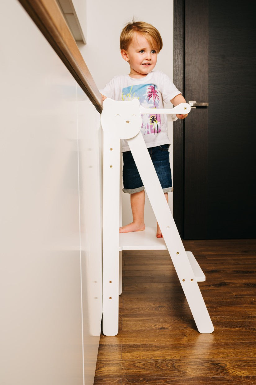 foldable baltic birch step stool for kids folded flat against a wall in a tidy kitchen