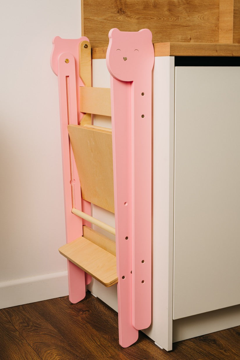 foldable baltic birch step stool for kids folded flat against a wall in a tidy kitchen