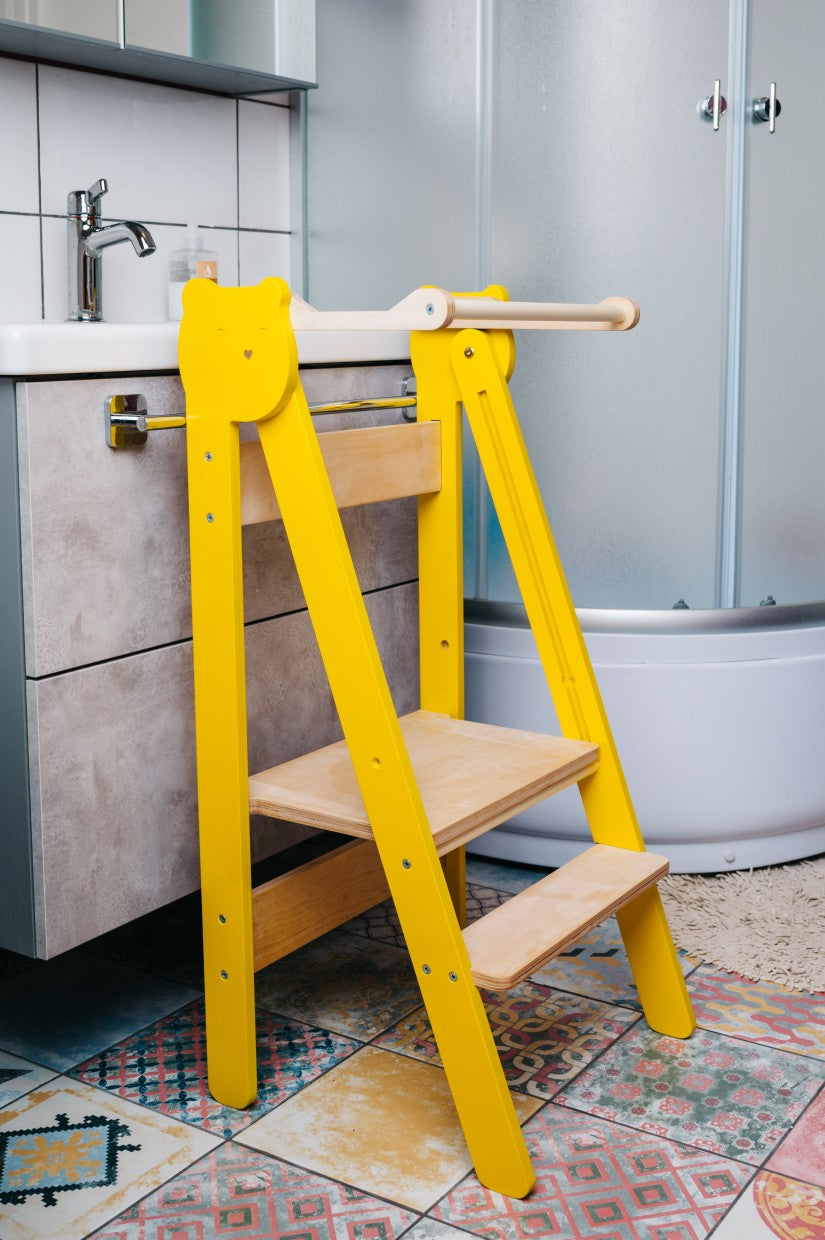 foldable baltic birch step stool folded flat against a wall in a tidy kitchen