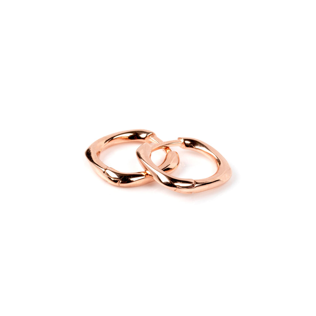 bold close-up of elegant square hoop earrings in rose gold on a dark background