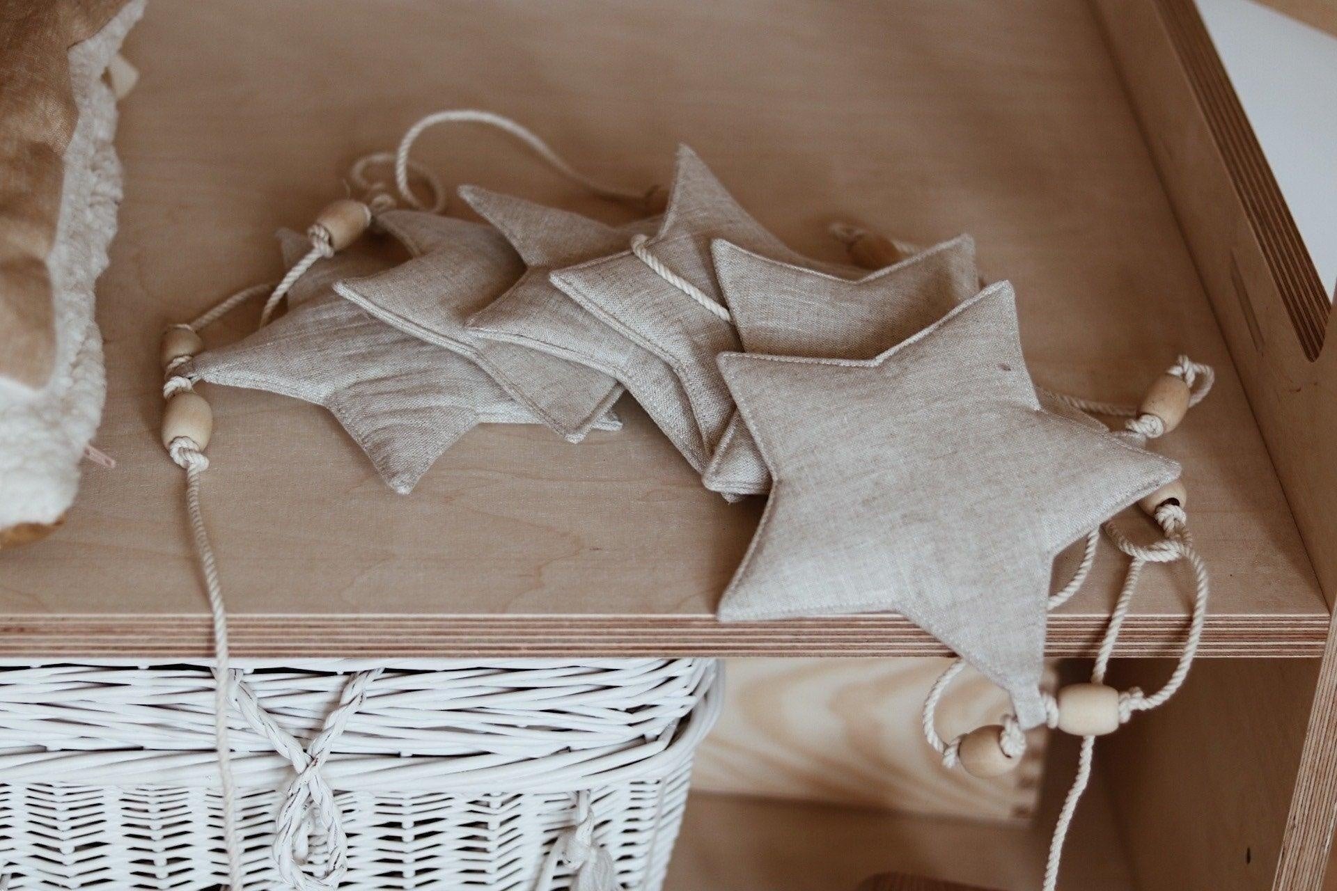 soft linen sand star garland draped gently over a nursery shelf with warm morning light
