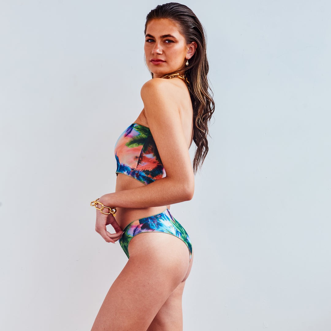 soft electric palm tan-through bikini set laid on a sandy beach