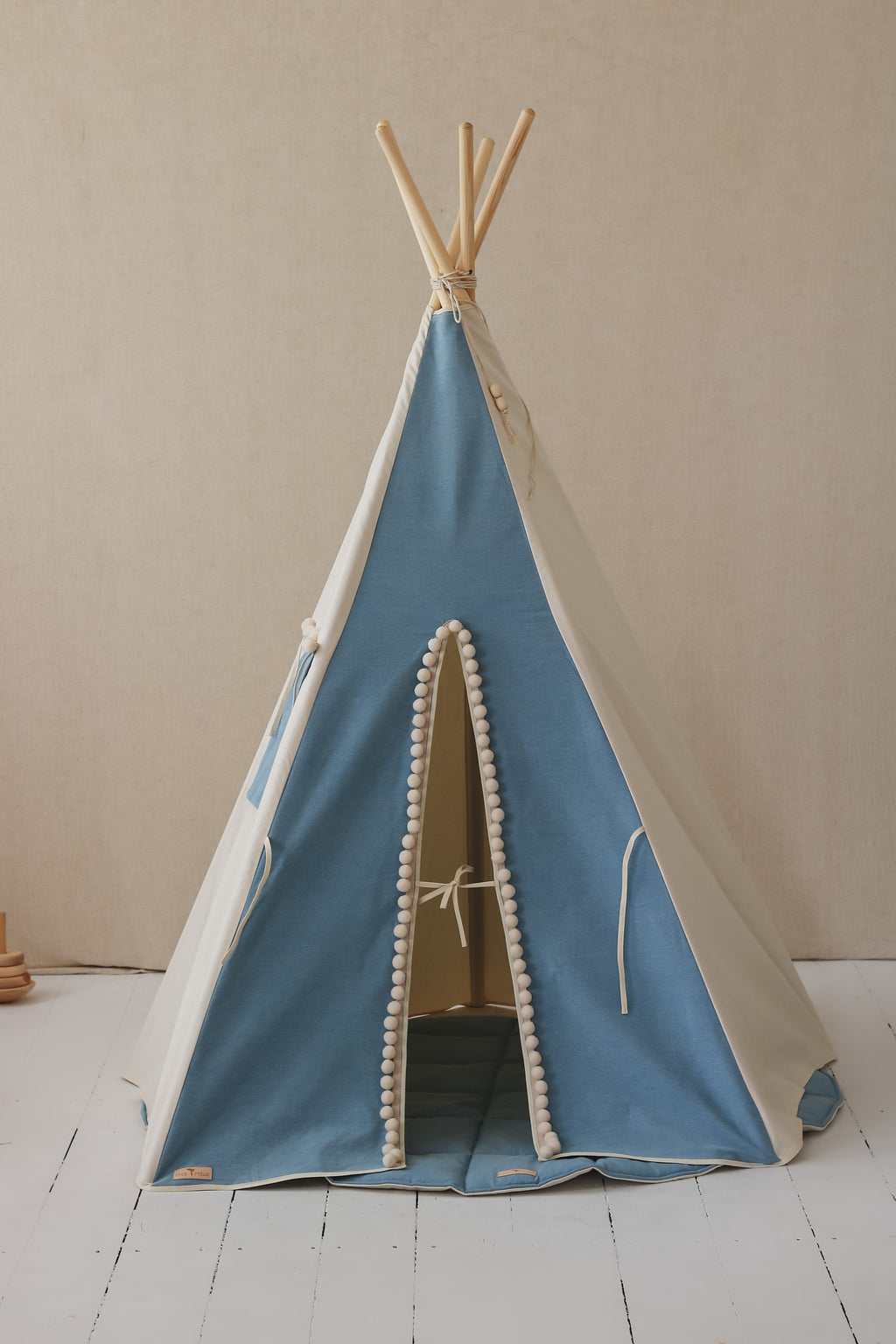 elegant handmade cotton teepee tent with playful pompoms, a refined kids' playroom hideaway