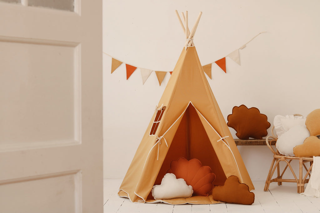 orange kids teepee tent with pine poles and cotton cover on a sunny lawn