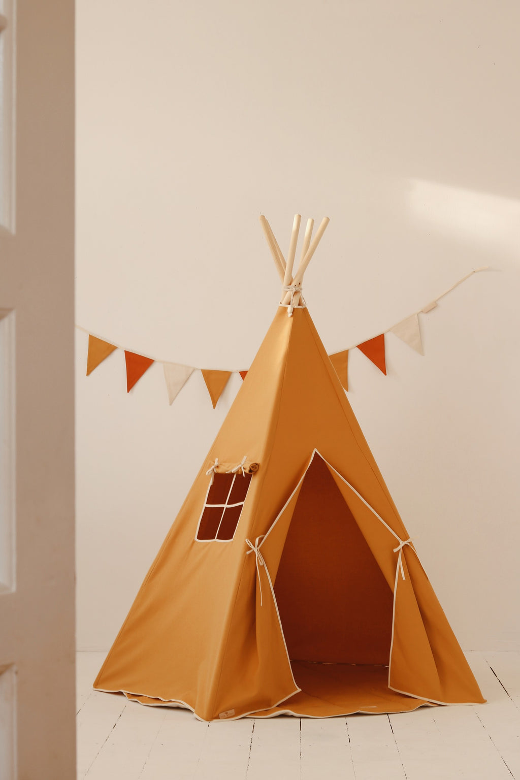 handcrafted orange kids teepee tent with pine poles in a sunlit garden