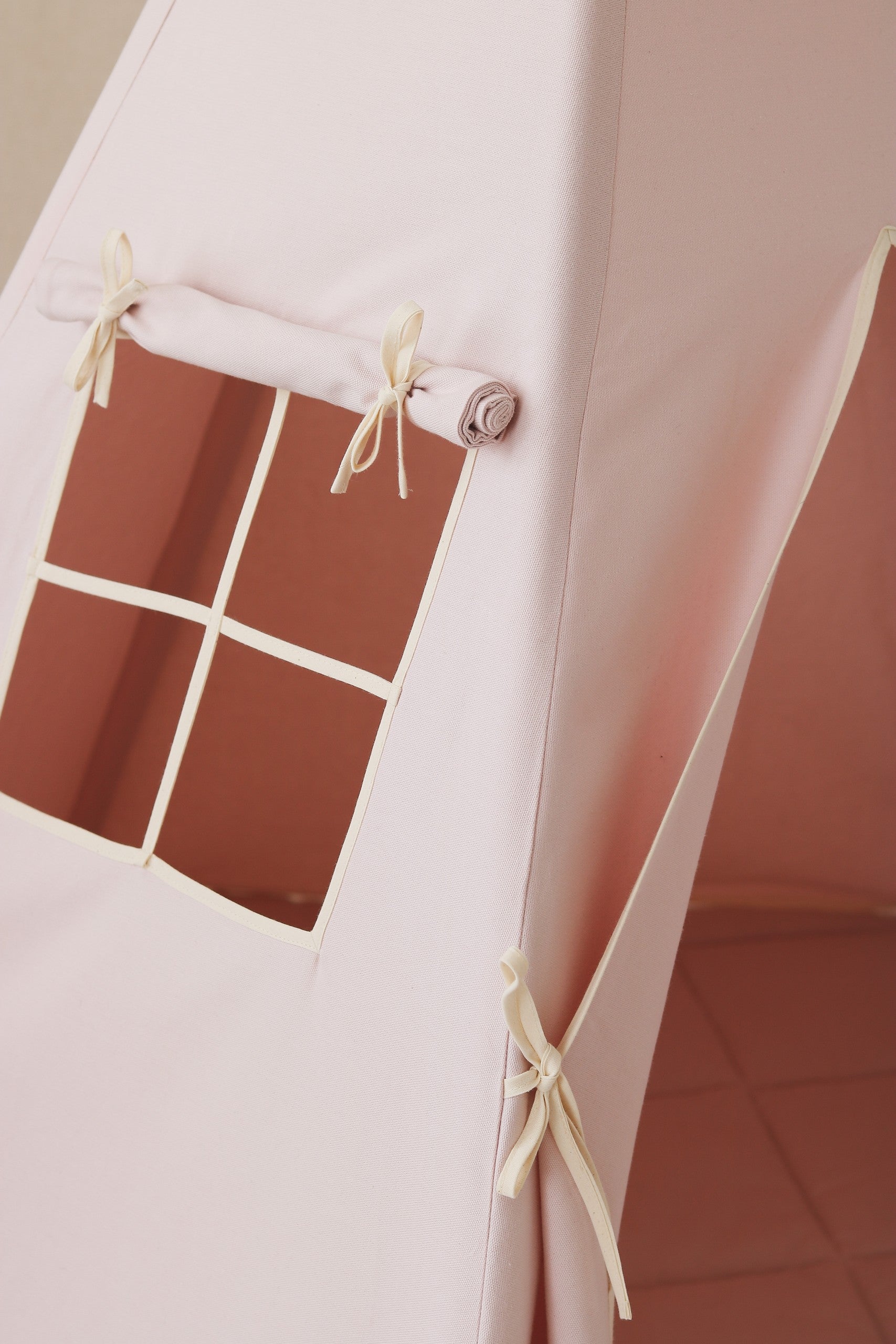 elegant pastel pink kids teepee tent with natural pine poles in a refined nursery setting