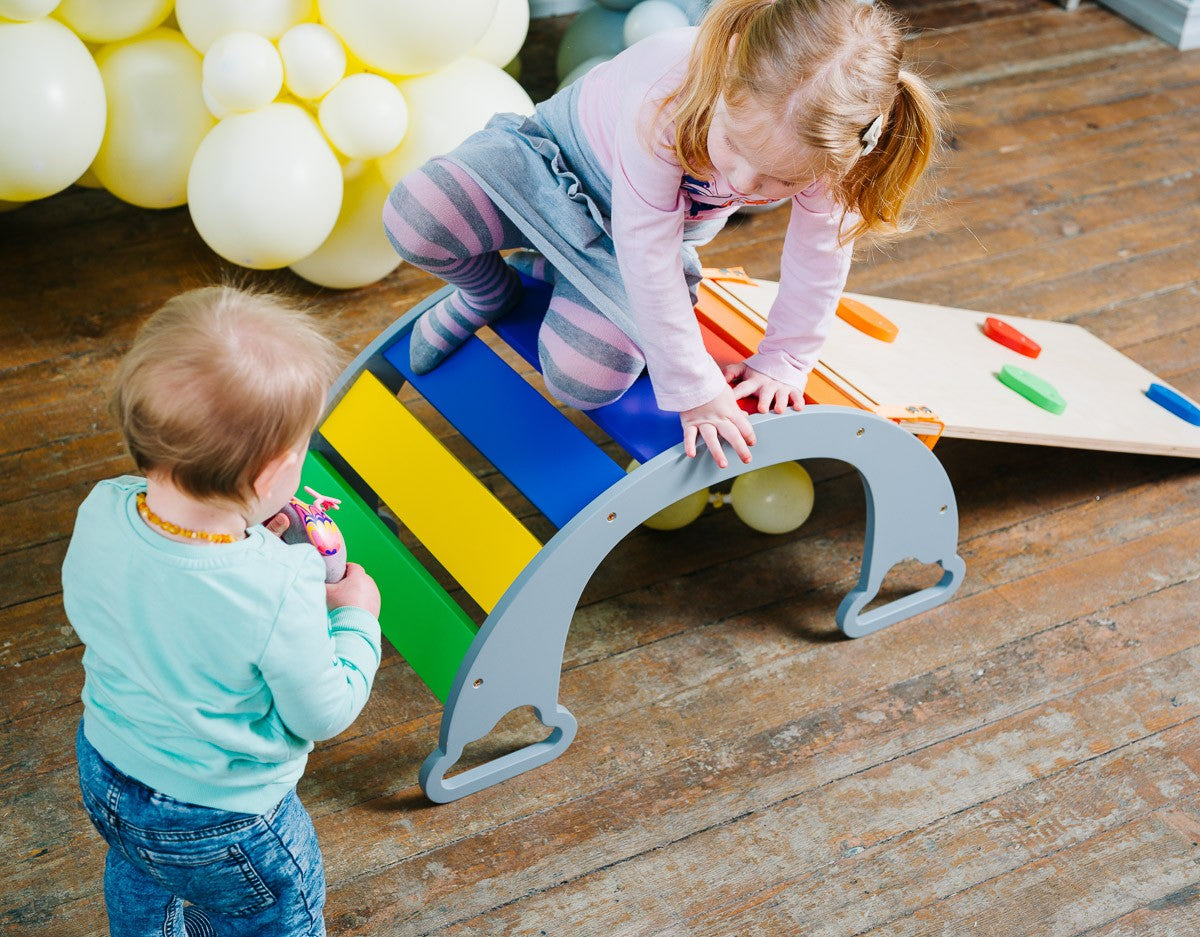 child sliding down the vibrant rainbow climber in a sunlit playroom