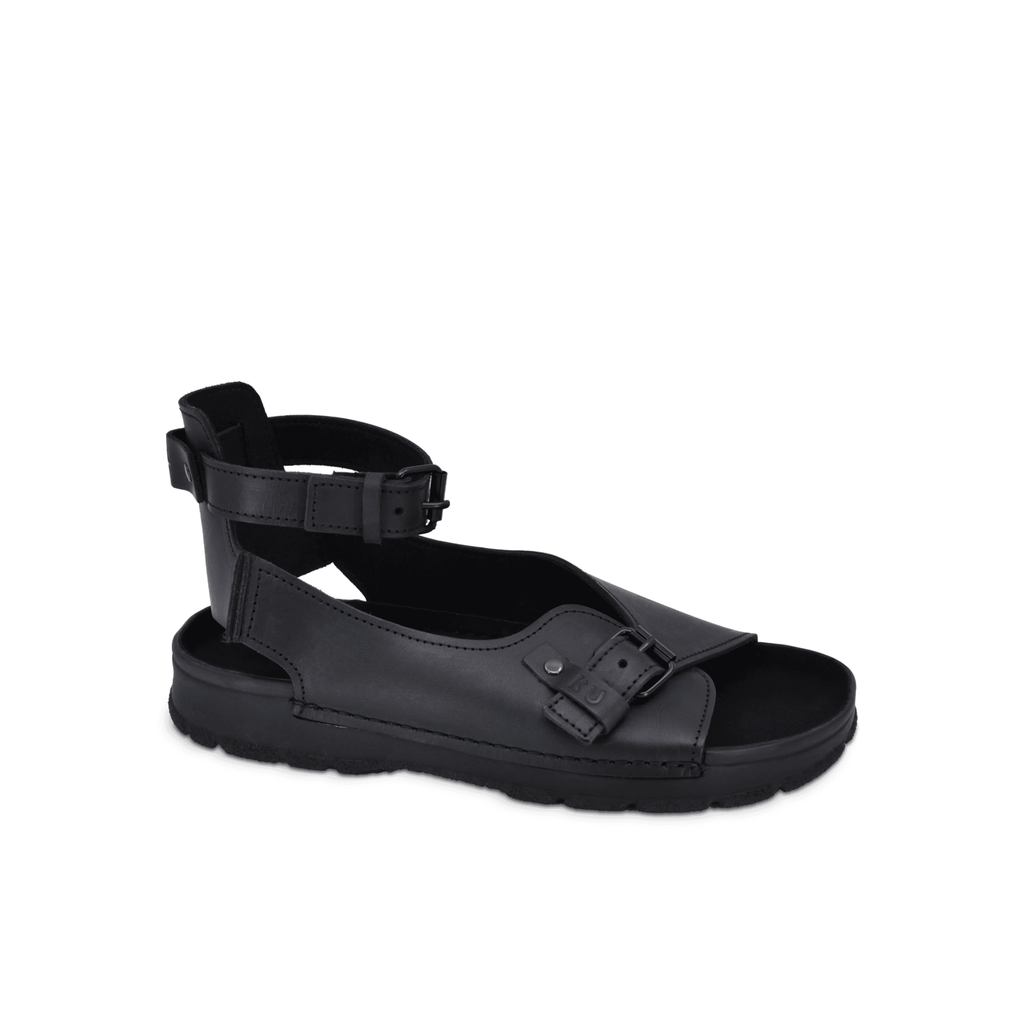 soft black leather athens sandals from toku, shown from a gentle side angle on a cozy background