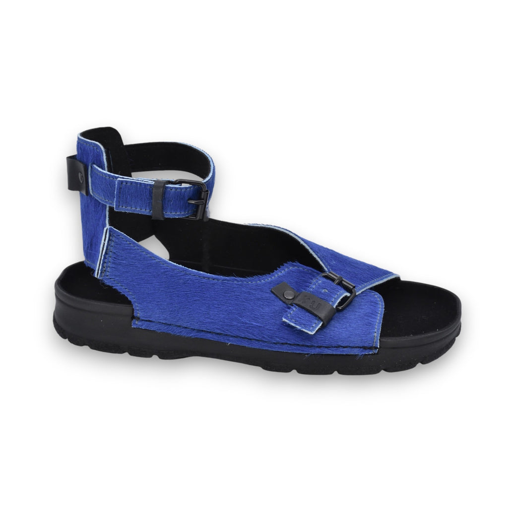 playful blue leather athens sandals on a sunlit stone path, showing the adjustable ankle strap