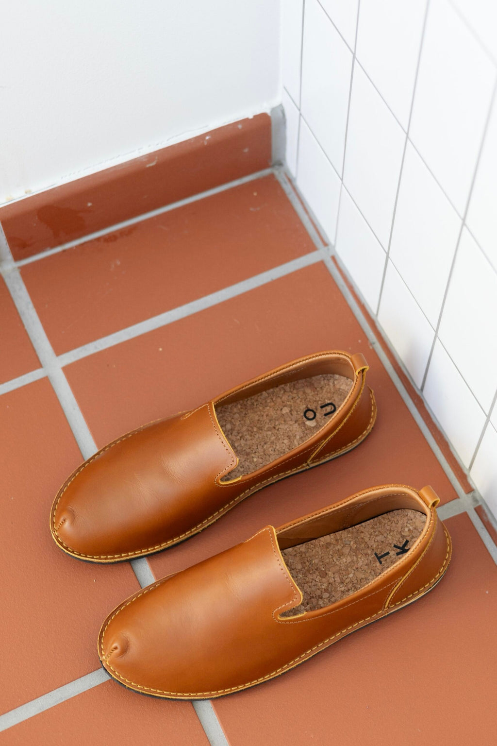 elegant ocre leather loafers on a marble surface, showcasing their refined silhouette and artisan-crafted details