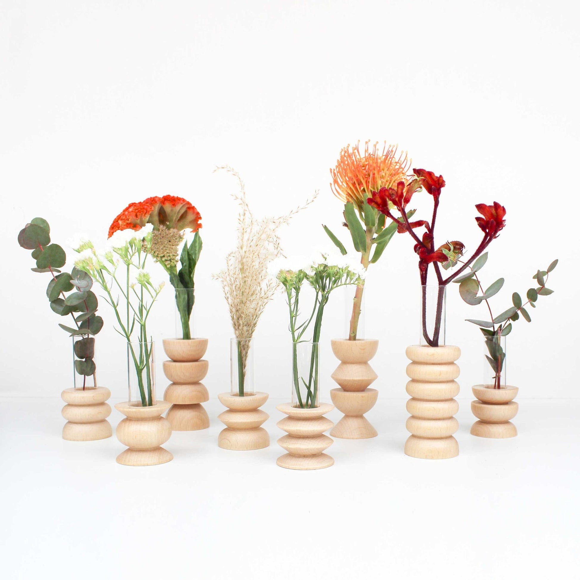 practical wooden vase with glass insert for fresh flowers on a kitchen counter