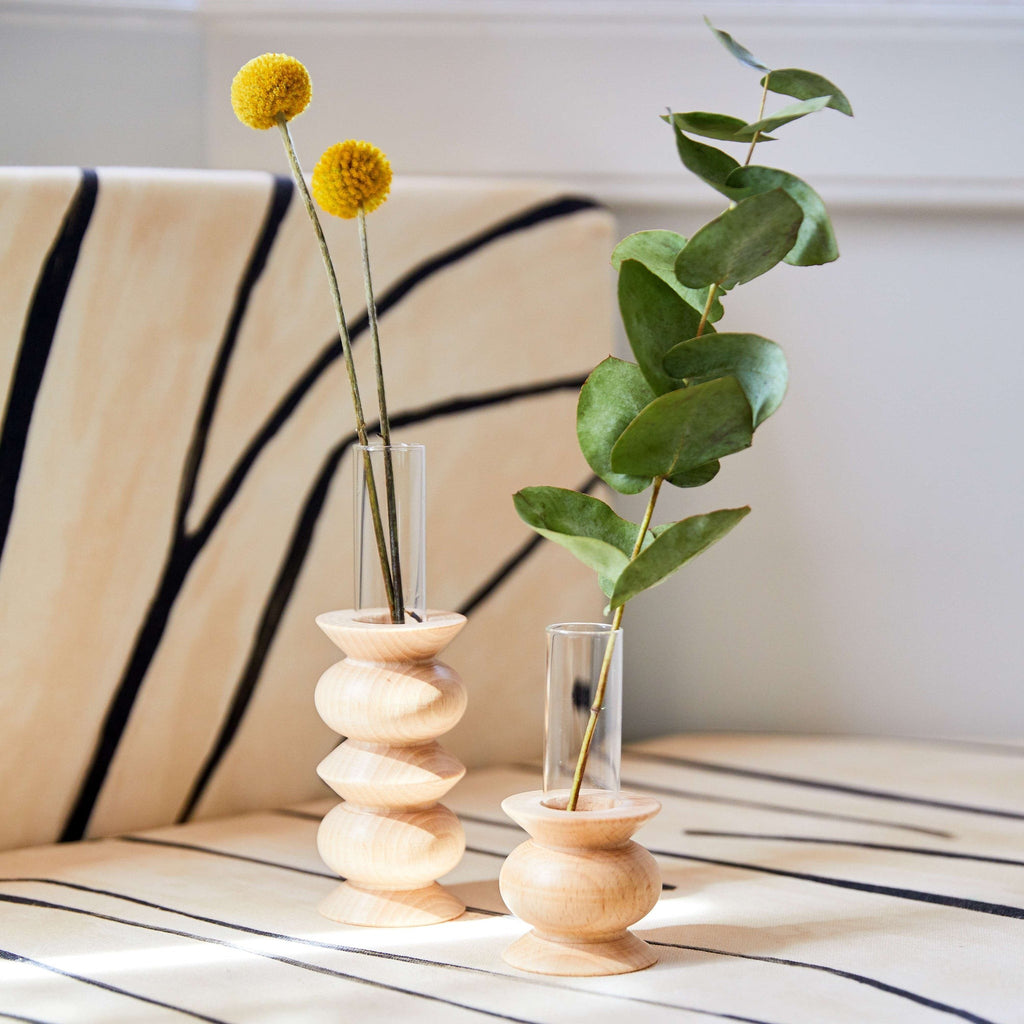 playful beech wood totem vase with a single bright flower on a sunlit desk